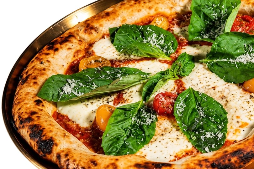 Close-up of a pizza with melted mozzarella, fresh basil, cherry tomatoes, and grated cheese.